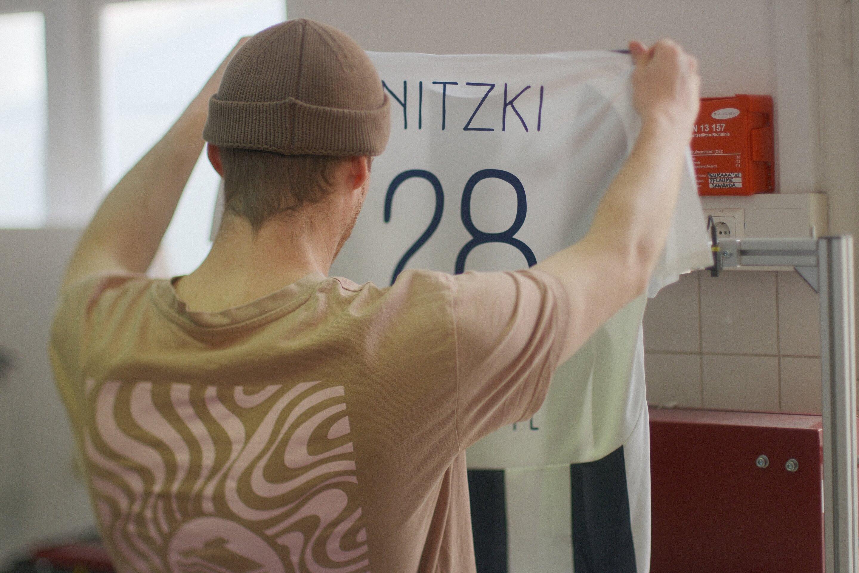 Markus von Aus'm Keller hält ein fertig bedrucktes Vereinstrikot mit Namen NITZKI und Nummer 28 hoch