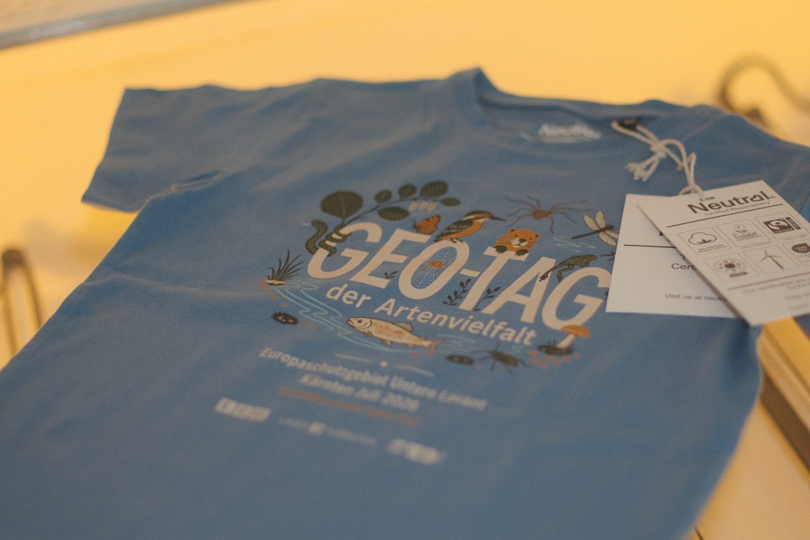 Hellblaues Fairtrade-T-Shirt von Neutral mit vollfarbigem DTF-Druck „Geo-Tag der Artenvielfalt