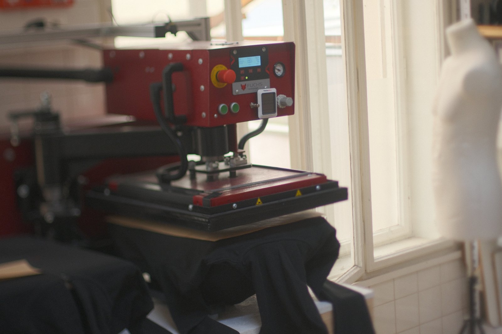Thermopresse beim DTF-Transfer auf eine schwarze Zipperjacke der FH Joanneum