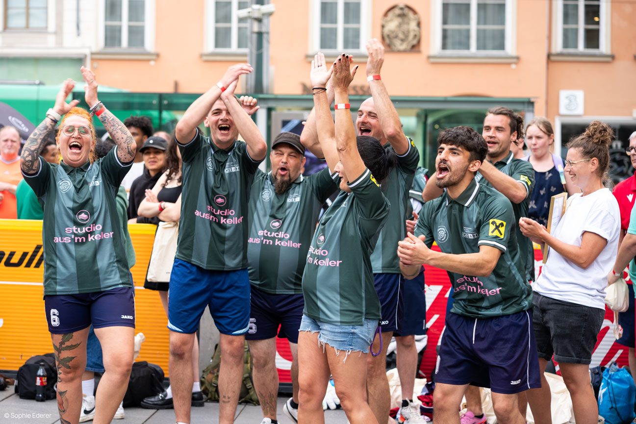Jubelndes Team in grünen streetfootbALL-Trikots mit „studio aus'm keller