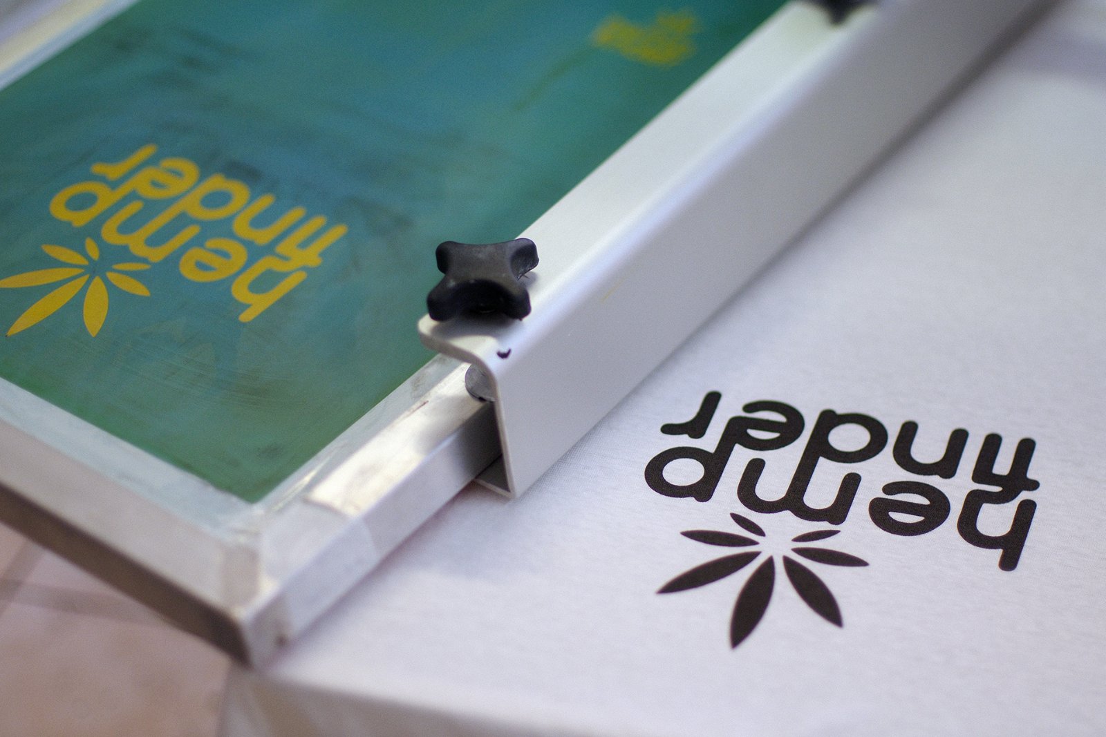 Siebdruck am Handdruck-Karussell — das hemp-finder-Motiv frisch in Algenfarbe auf das Hanf-Shirt gedruckt