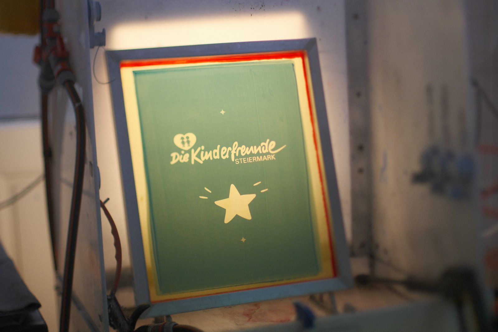 Beschichtetes Siebdruck-Sieb mit Kinderfreunde-Steiermark-Logo und Stern-Motiv im Belichtungs-Setup für den wasserbasierten 1C-Siebdruck