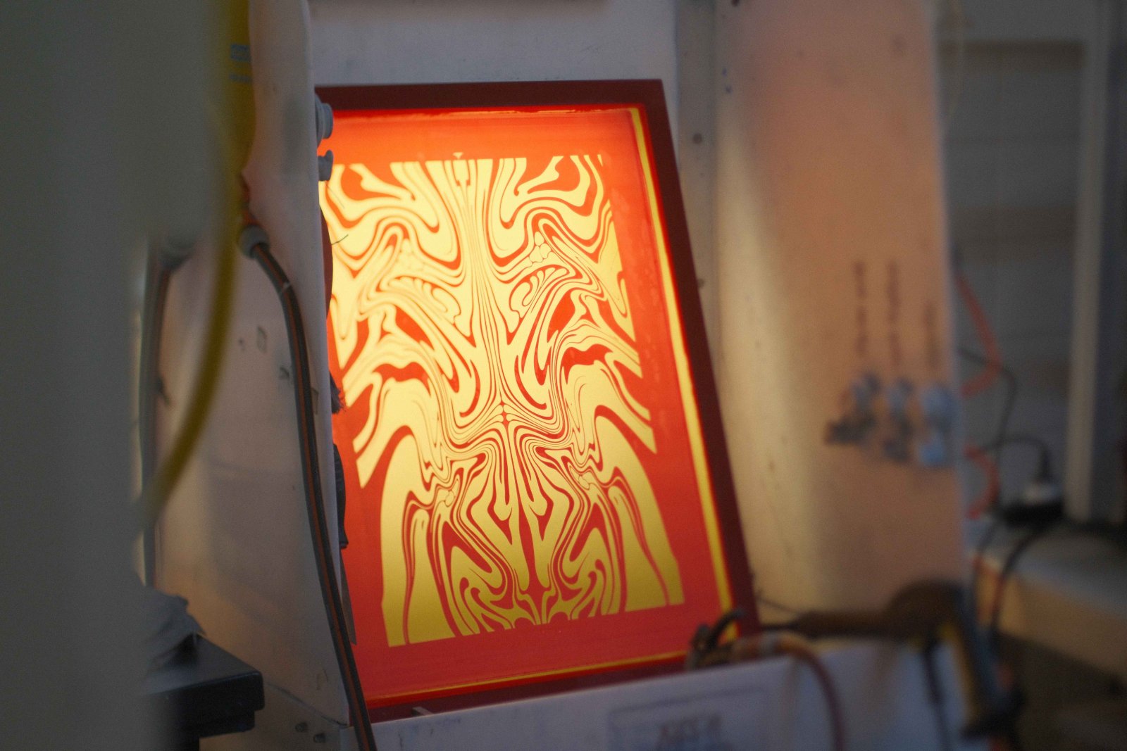 Belichtetes Siebdruck-Sieb mit dem Swirl-Motiv, durchleuchtet — die feine Linienstruktur des Discharge-Designs