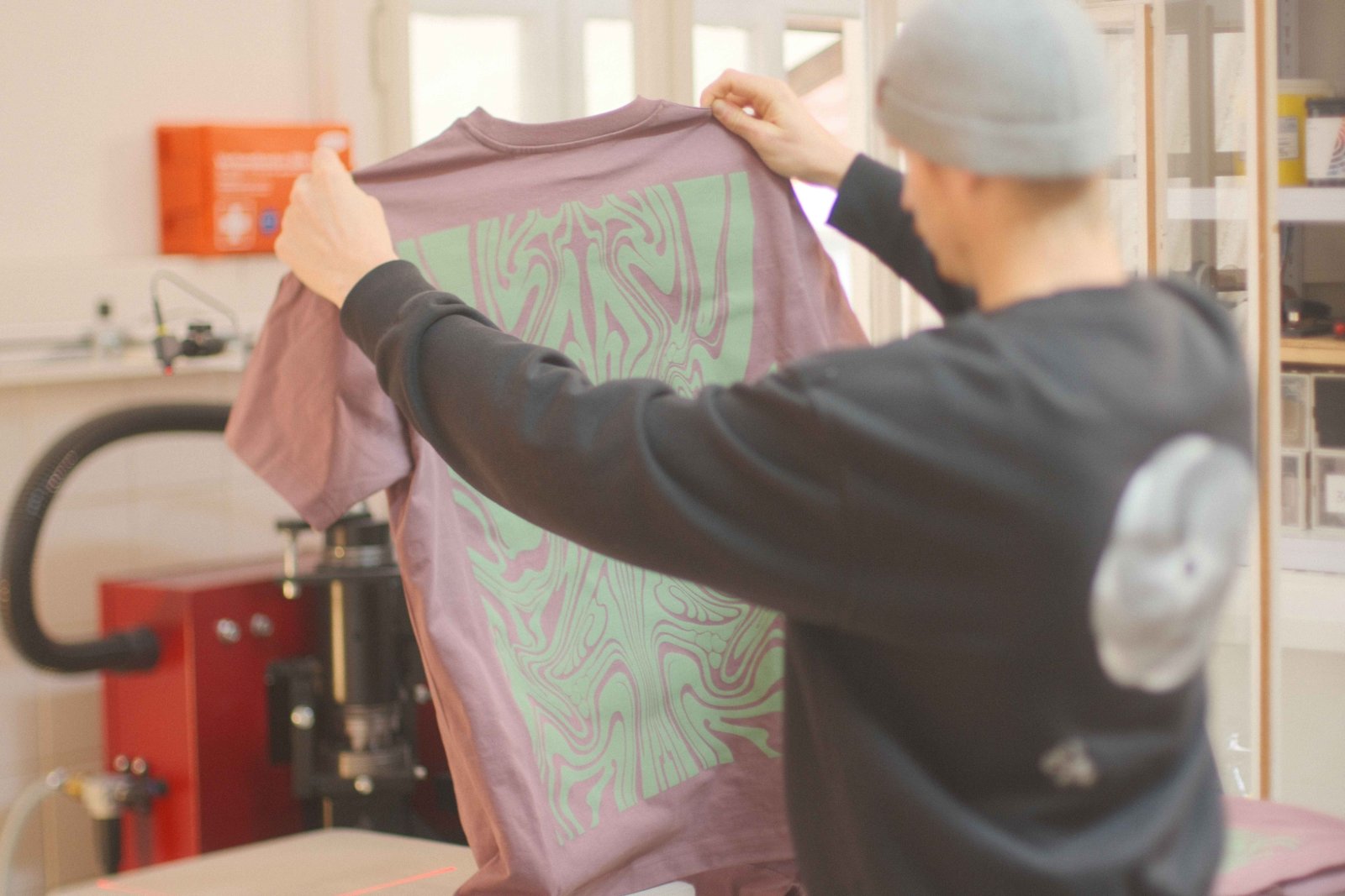Fertiges Maskusi-Ink-Oversized-Shirt wird hochgehalten — großflächiger Discharge-Swirl-Backprint