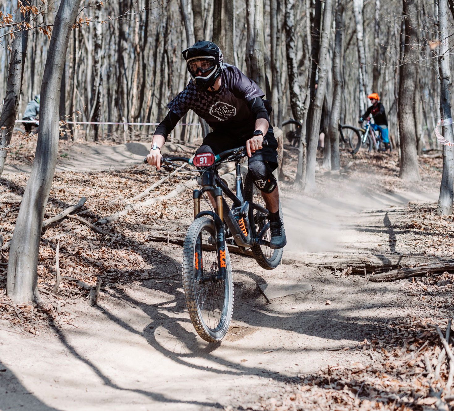 Mountainbiker im Radlager-Trikot mit Lend-Bikes-Vinyl-Print springt über einen Waldtrail