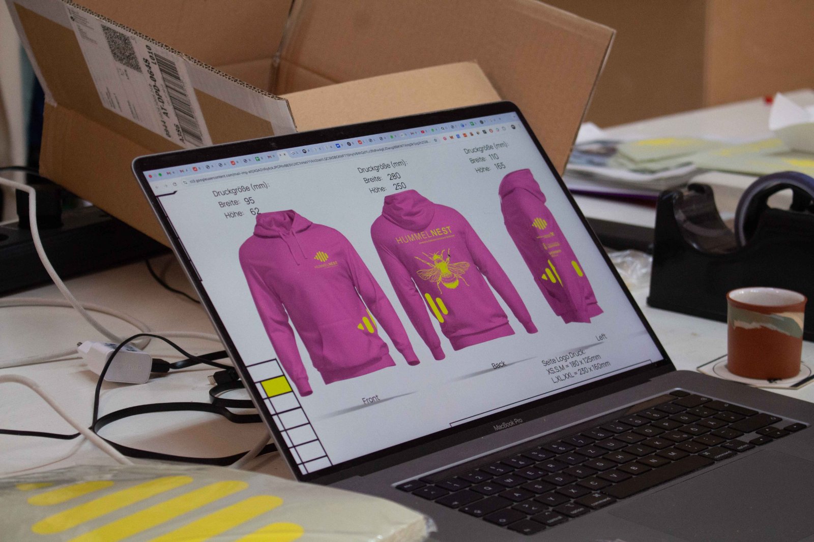 Druckdaten-Aufbereitung am Laptop — Hummelnest-Hoodie-Mockup mit Druckmaßen für Brust, Backprint und Ärmel