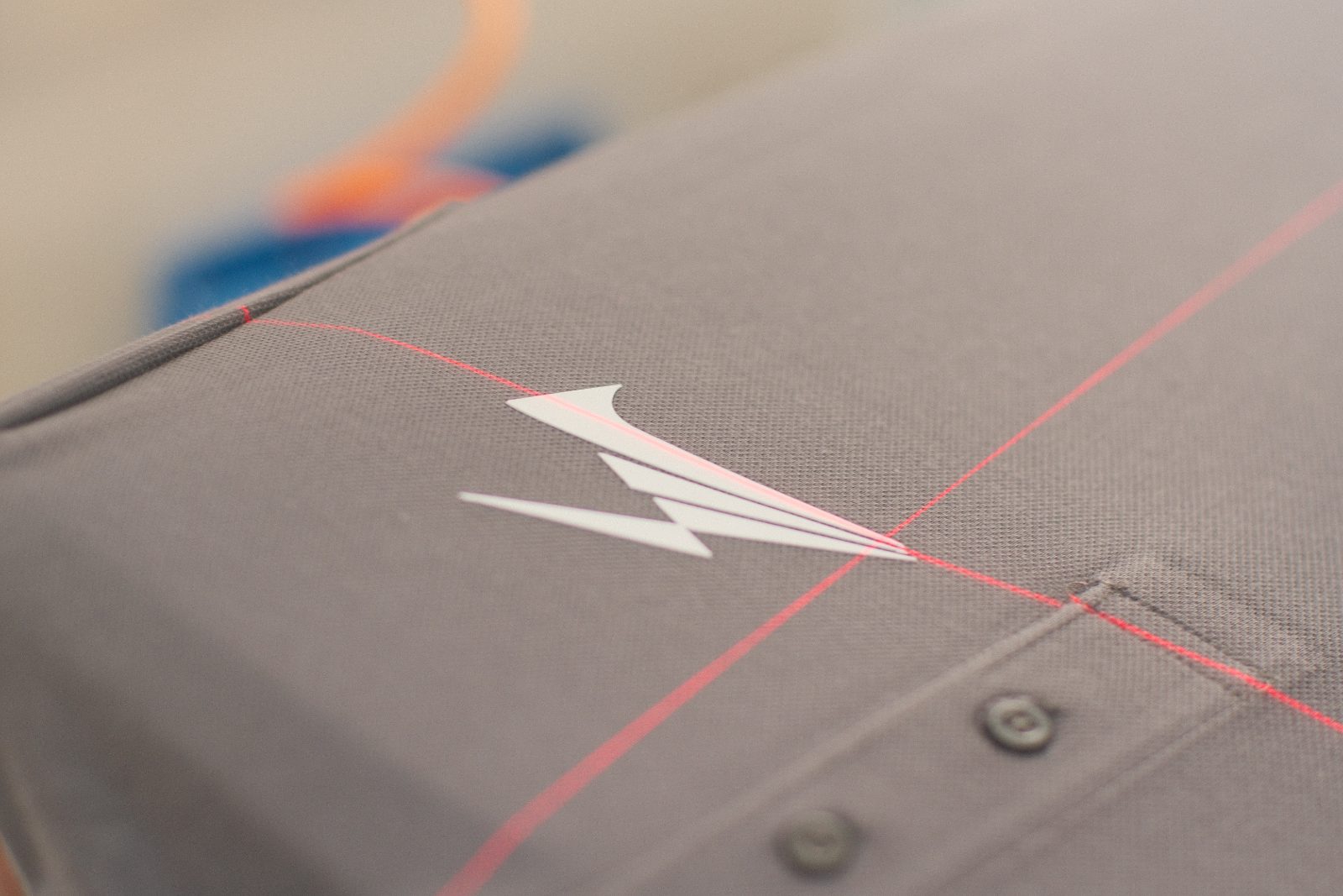 Nahaufnahme eines weißen, erhabenen 3D-Silikon-Aufdrucks auf grauem Arbeitspoloshirt — die feinen Linien der Motive stehen sichtbar vom Stoff ab
