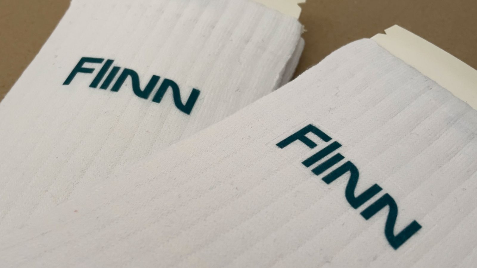Zwei weiße Crew-Socken mit petrolfarbenem „FINN