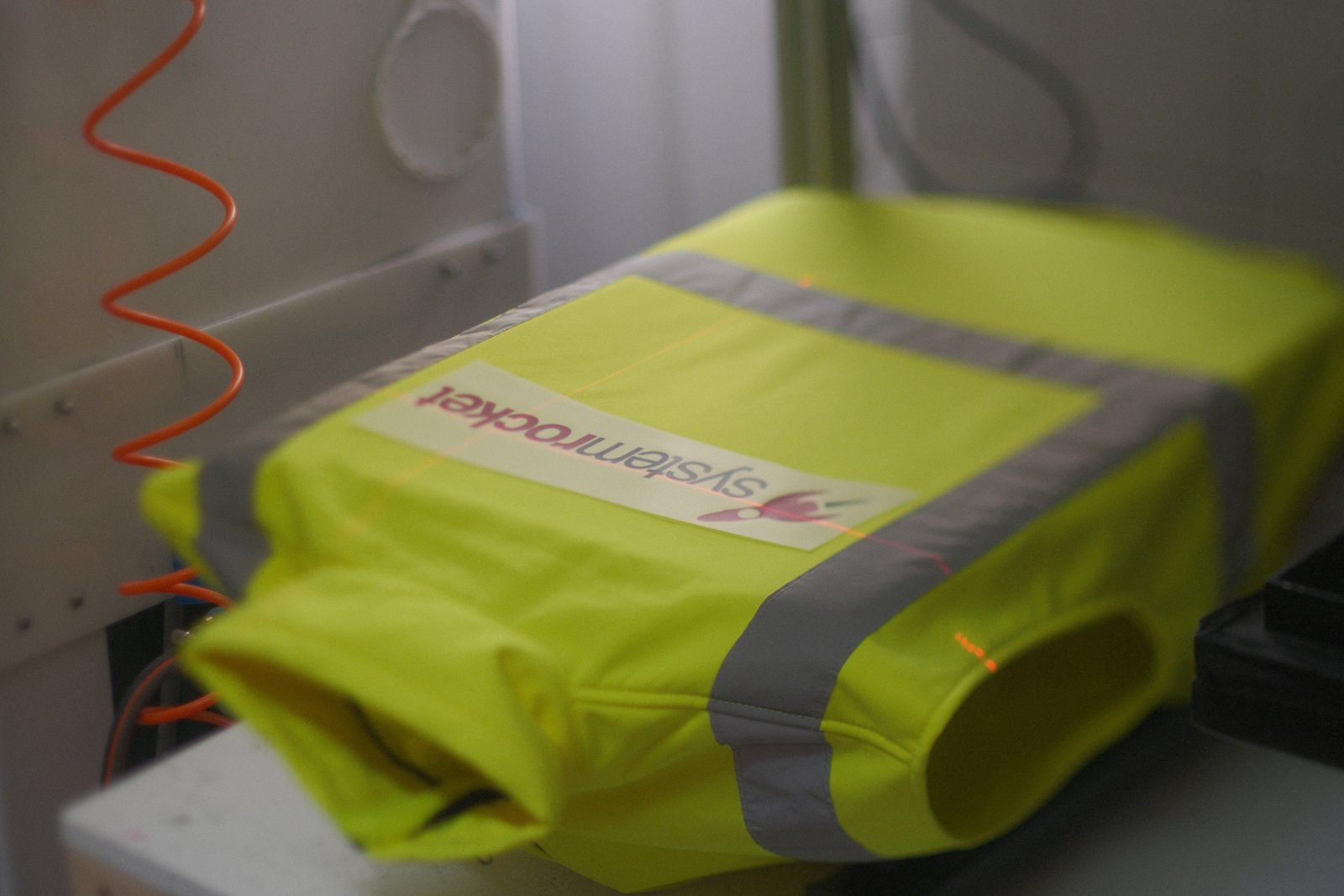 Industrie-DTF-Transferpapier mit Systemrocket-Logo wird auf die fluoreszierende Warnweste aufgepresst
