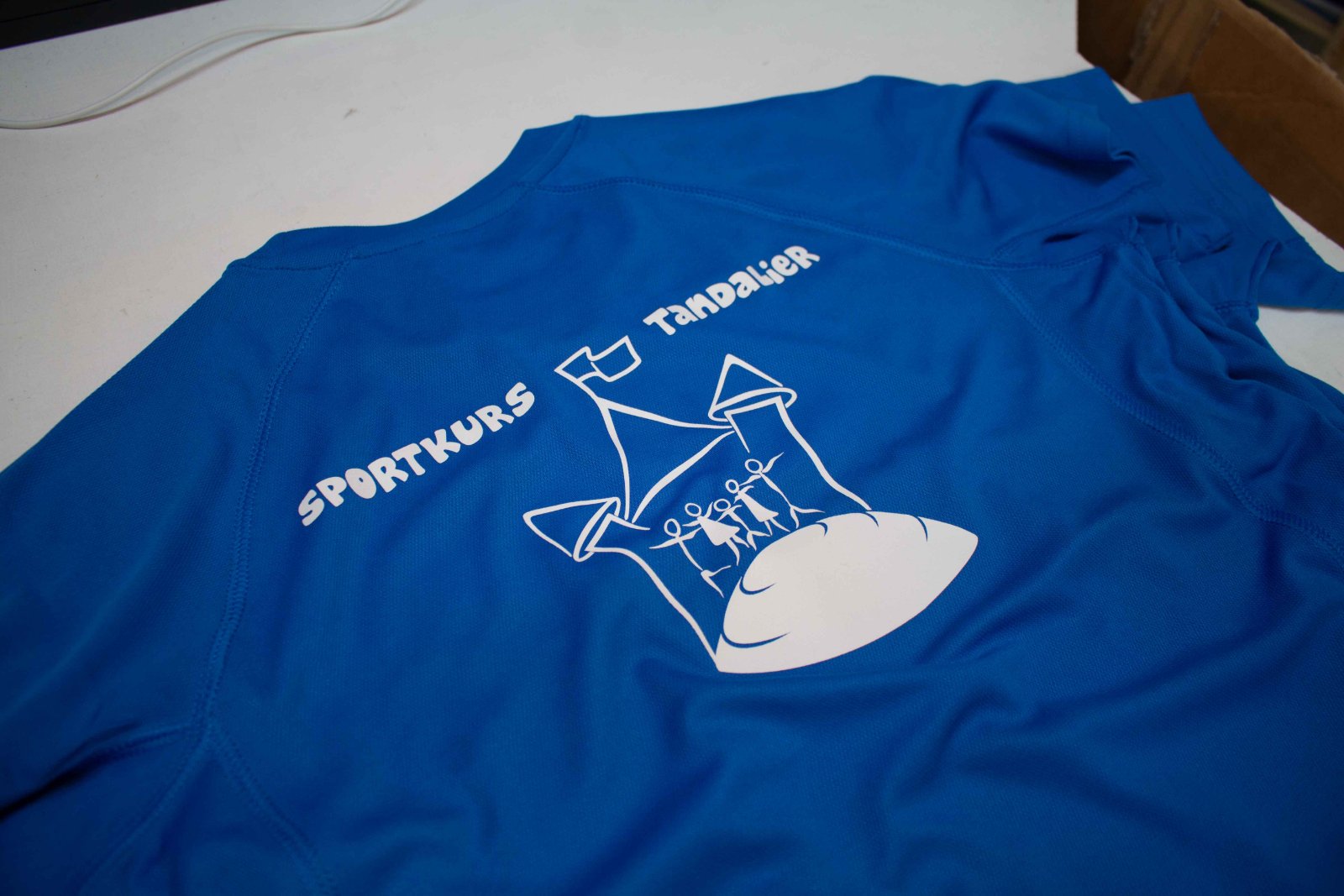 Blaues Funktions-Sport-Trikot des Sportcamps Tandalier mit weißem Sportkurs-Logo aus Sport-Vinyl