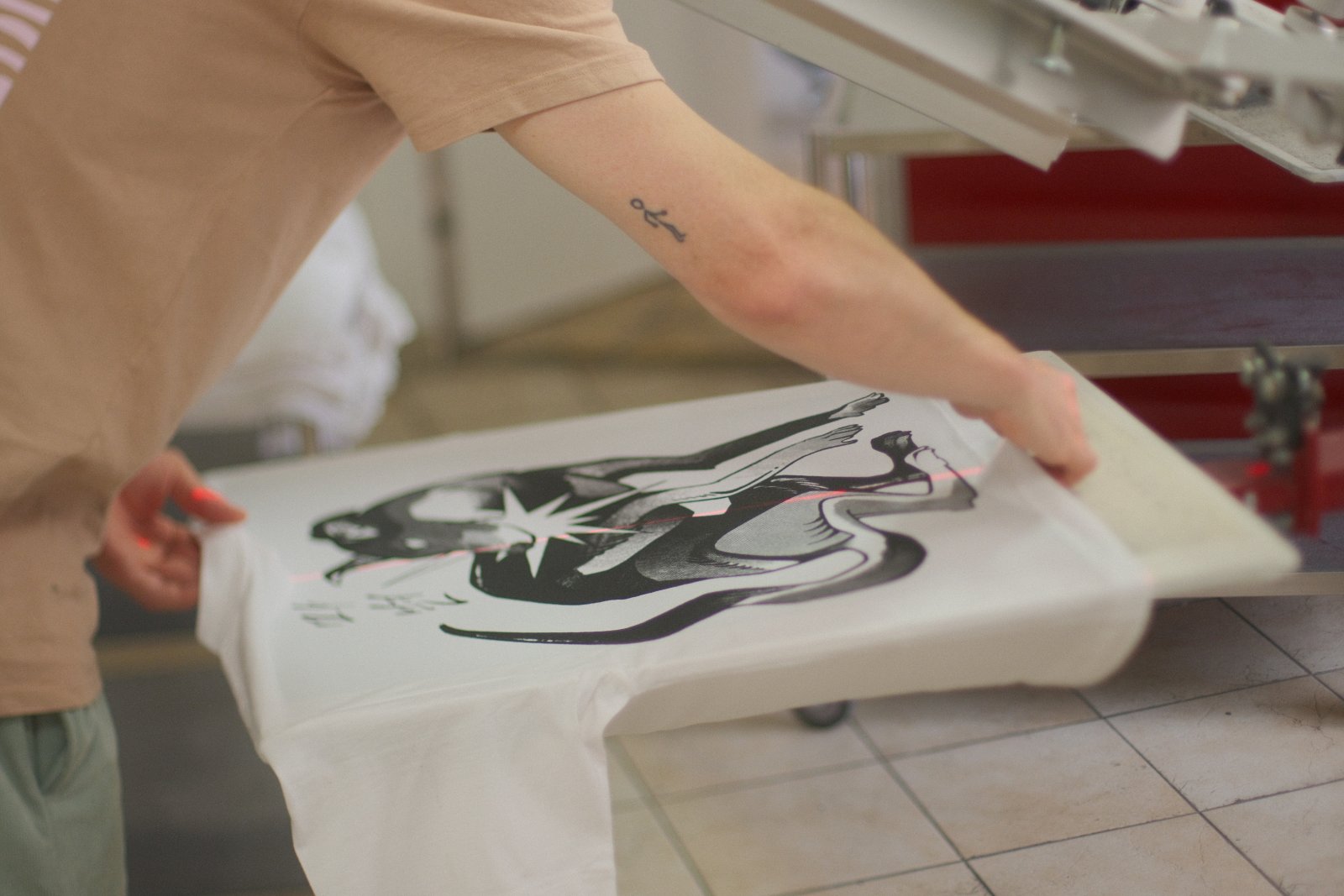 Frisch bedrucktes Shirt wird vom Platen genommen — Laser-Ausrichtung sichtbar