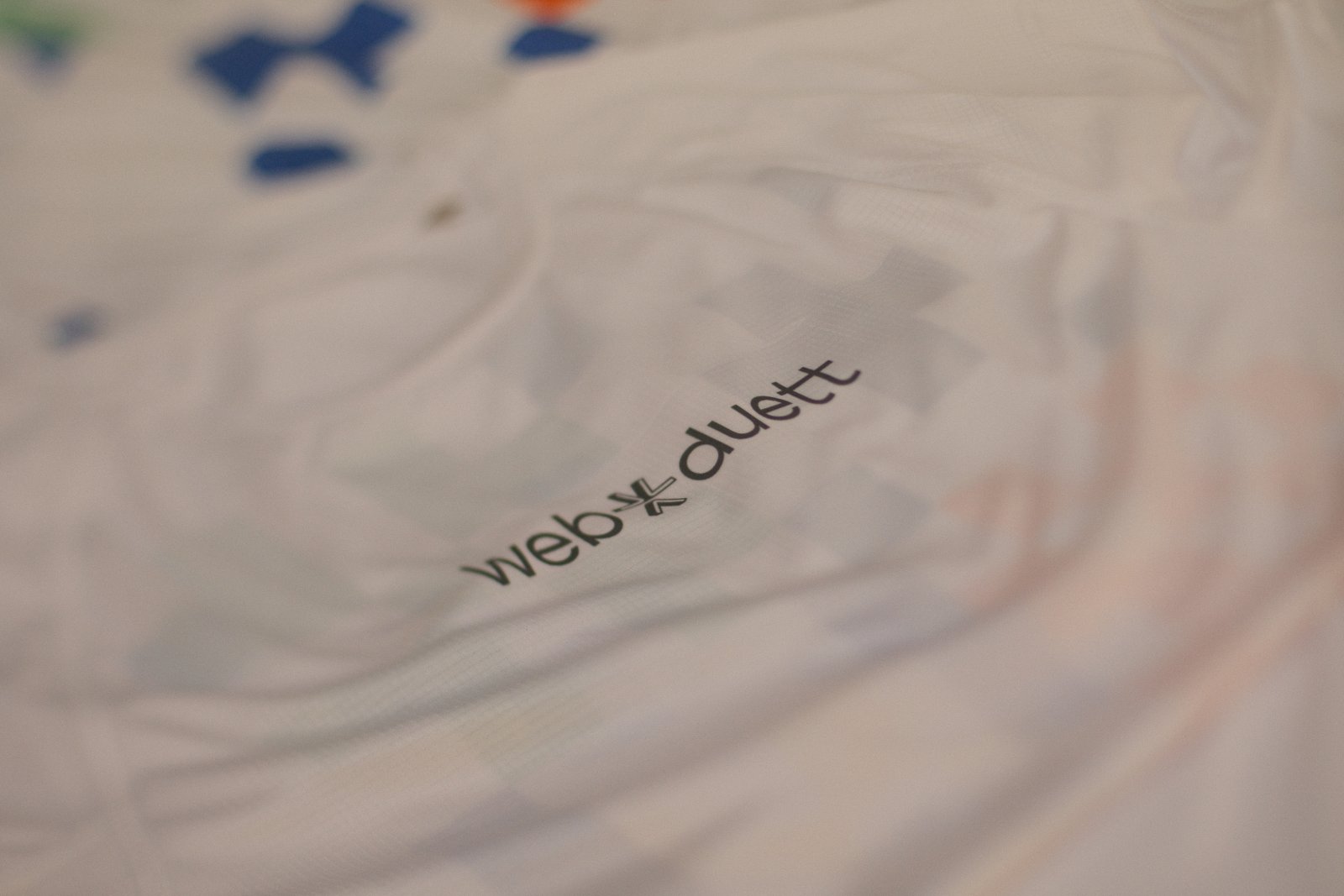 Weißes Brand-Shirt der Softwareagentur Webduett auf Schneiderpuppe — dezenter web-duett-Logodruck vorne, Allover-Pixel-Pattern als Sublimationsdruck